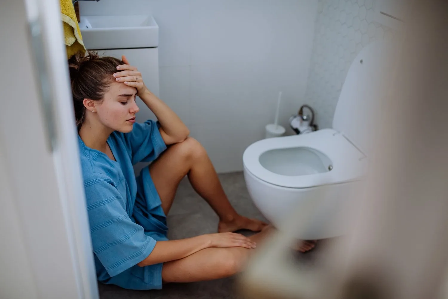 Adult client sitting in a bathroom during a severe nausea episode.